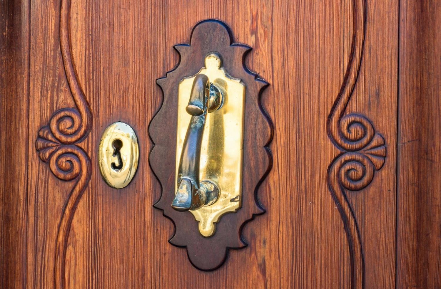 Close-up of a brass handle and keyhole on a solid wooden armored door